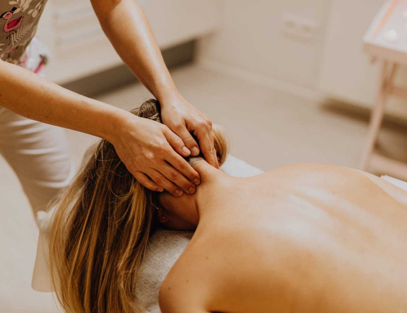 Person receiving a neck massage in a calm spa setting, highlighting relaxation and wellness.